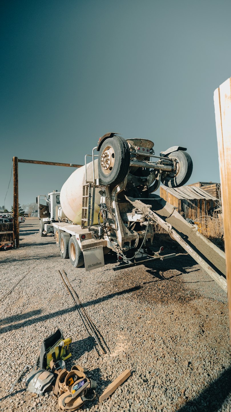 A concrete mixer truck pours wet cement onto a gravel lot.
