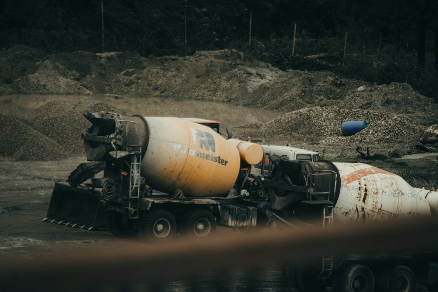 Two concrete mixer trucks parked on a construction site.