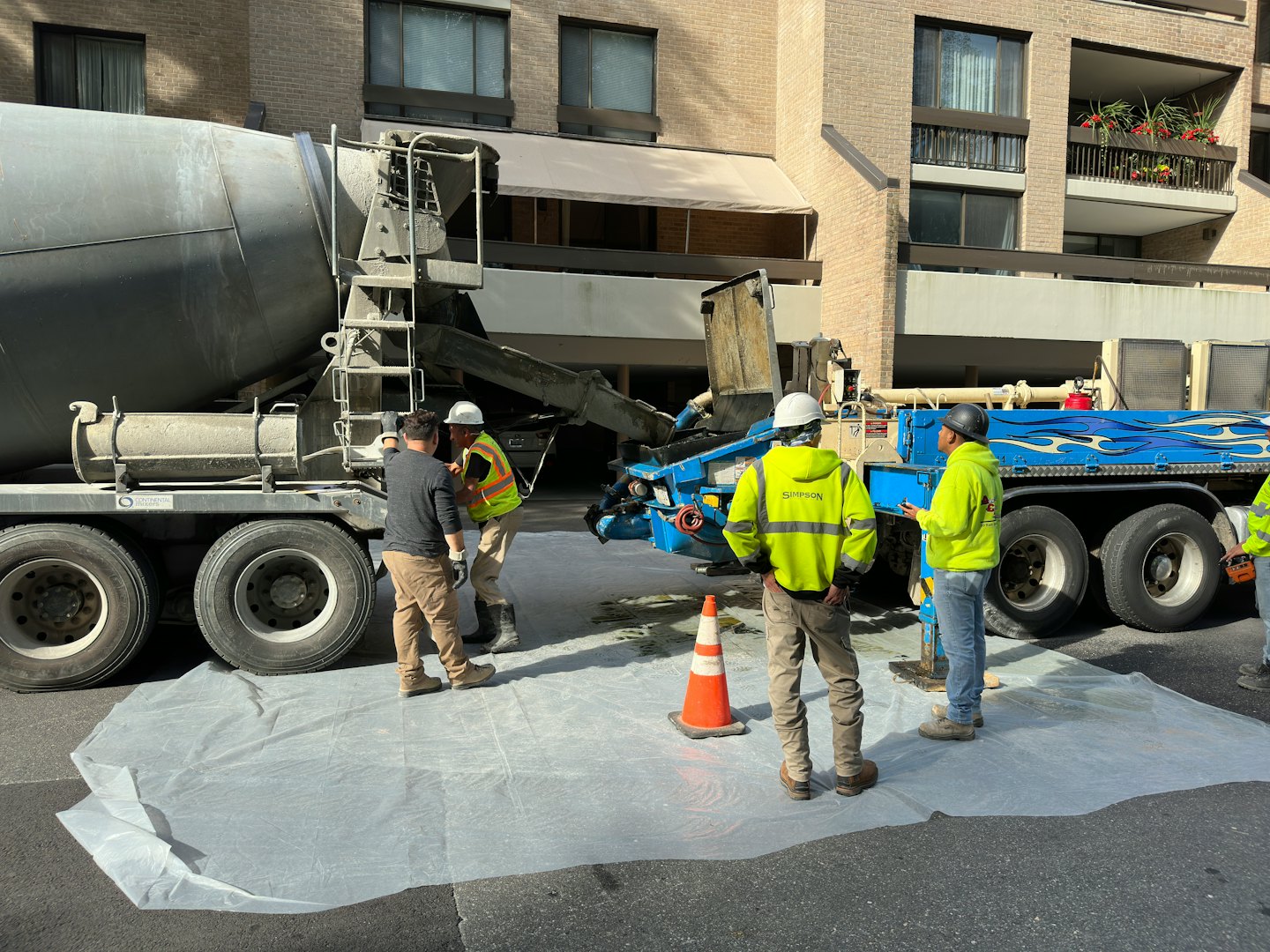 Construction workers prepare to pour concrete from a mixer truck.